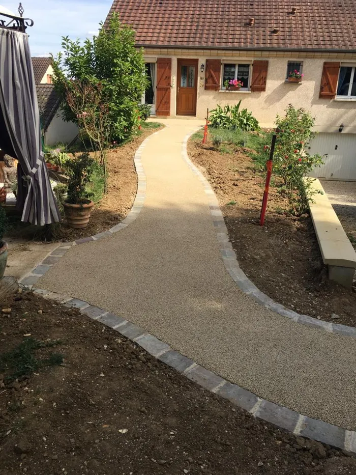 Allée piétonne claire bordée de pavés jusqu'à l'entrée de la maison