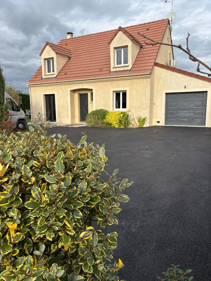 Allée et cour en enrobé noir devant une maison avec garage